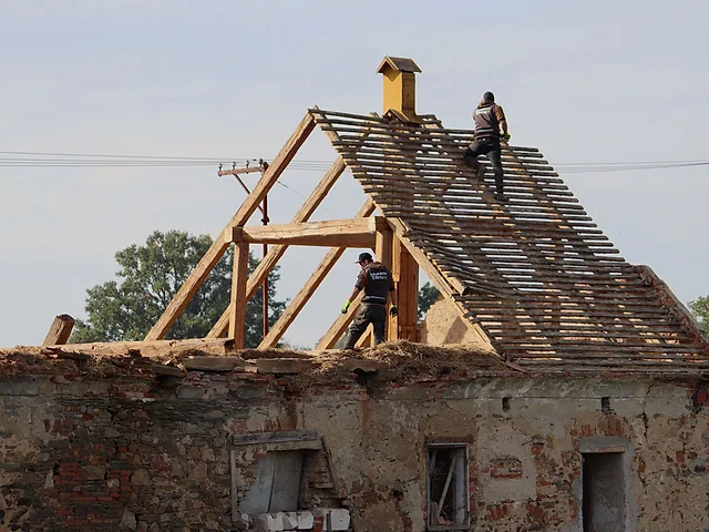 Dělníci rozebírají krov starého stavení